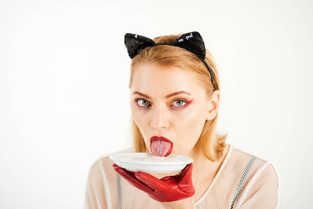 Ecology product and heath. Cat woman eat sour cream. Dieting and health. Sexy cat woman lick milk from plate. Food and drink. Girl in kitten ears and red gloves with yoghurt isolated on white. - Fotografie, Obrázek