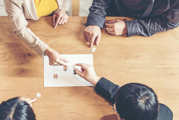 Businessman team work holding two jigsaw connecting couple puzzle piece for matching to goals target, success and start up new project in office.  Business Concept. - Photo, Image