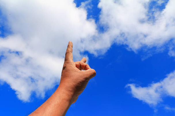 dłoni wskazując lub dotykania czegoś na tle niebieskiego nieba - Zdjęcie, obraz