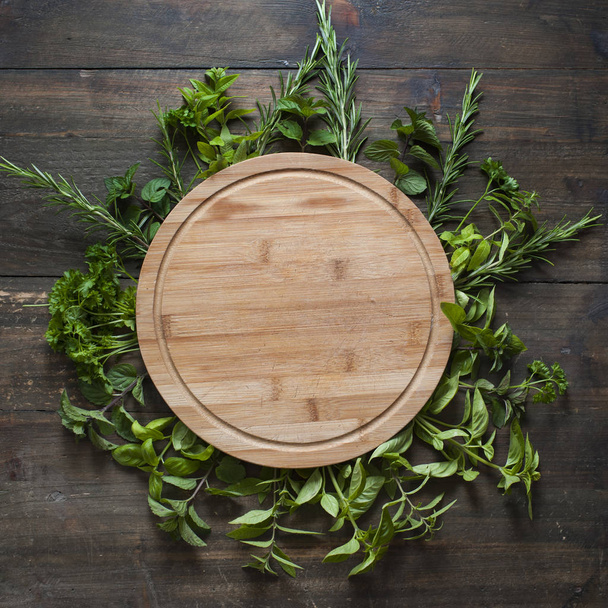 empty wooden cutting board with frame of freesh leafs - Photo, Image