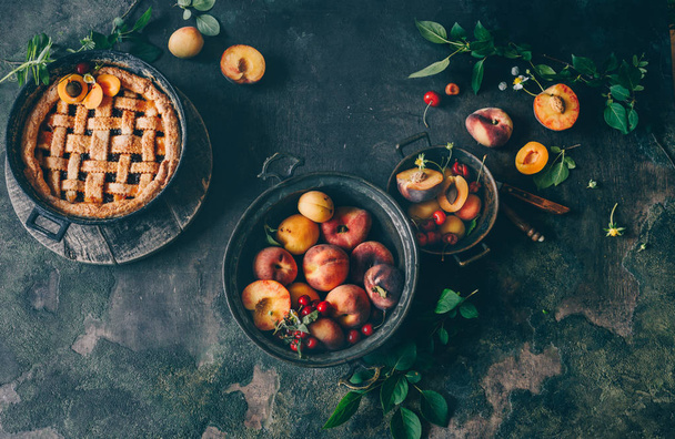 Fruit pie on colorful wooden rustic background with fresh peaches, beautiful food still life - Photo, image