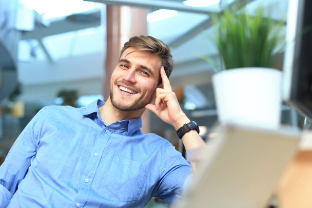 Portrait of happy man sitting at office desk, looking at camera, smiling. - Fotó, kép