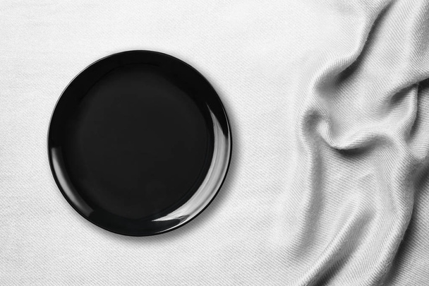 テーブルに白いテーブル クロスの上の黒空セラミック プレート トップ ビュー. - 写真・画像