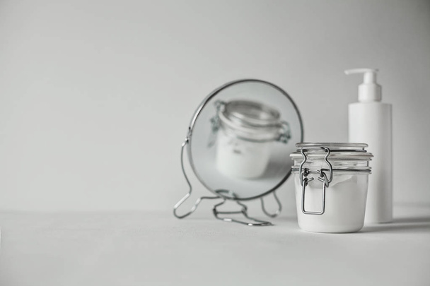 Красивый минималистский концептуальный все белое композиция - прозрачная банка и пластиковая бутылка с насосом, круглый зеркало, все белое с металлическими деталями
 - Фото, изображение