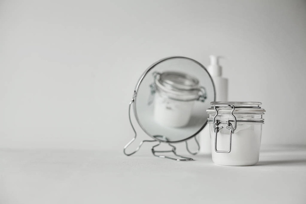Belo conceito minimalista toda a composição branca - frasco transparente e garrafa de plástico com bomba, espelho redondo, tudo branco com detalhes metálicos
 - Foto, Imagem