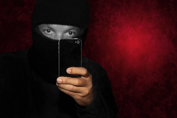 Böser Krimineller mit schwarzem Smartphone bereit für Raubüberfall oder Mord - Foto, Bild