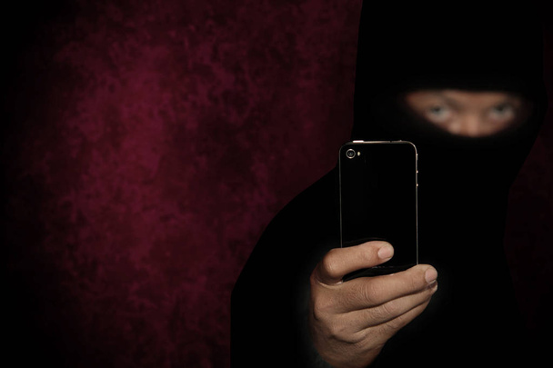 Criminale malvagio con smart phone nero pronto per la rapina o per commettere un omicidio
 - Foto, immagini