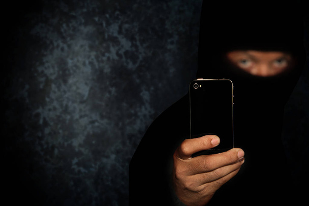 Criminale malvagio con smart phone nero pronto per la rapina o per commettere un omicidio
 - Foto, immagini