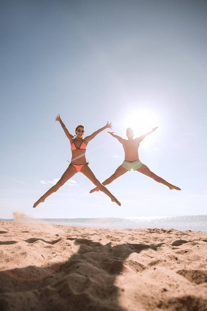 Picture of happy couple jumping on the beach. - Φωτογραφία, εικόνα