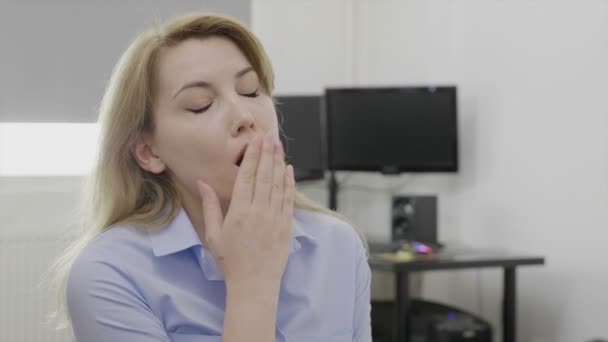 Blonde young sleepy employee at office desk yawning looking bored and tired - Záběry, video