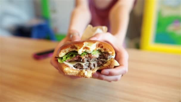 Big Burger in den Händen einer Frau. verschwommener Hintergrund. - Filmmaterial, Video