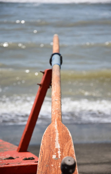 Um velho remo de madeira repousa em seu remo apontando para o mar
 - Foto, Imagem