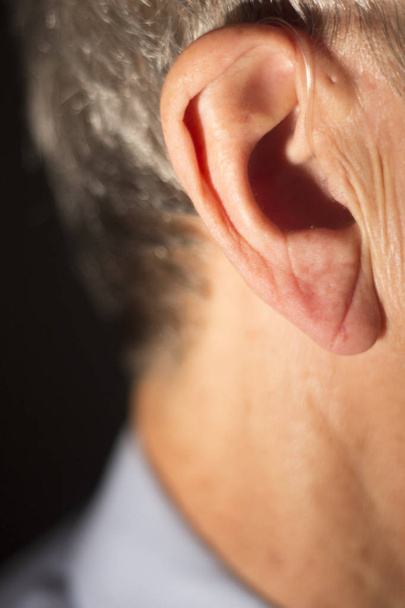 Deaf senior citizen man wearing modern digital high technology hearing aid in ear. - Photo, image