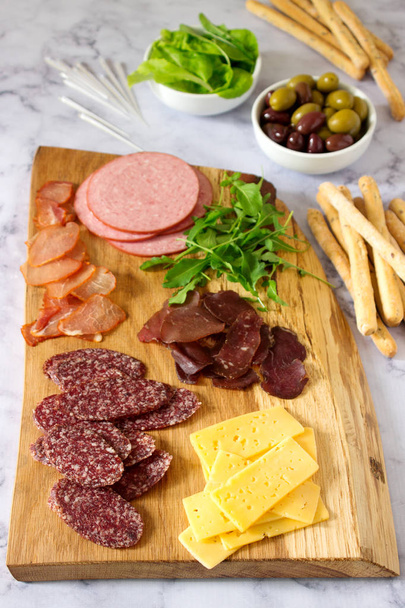 Appetizer table for wine or beer with sausages, dried meat and cheese, served with grissini, herbs and olives. Selective focus. - Foto, immagini