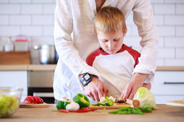 Image of man and his son preparing food at table with vegetables - Foto, Imagen
