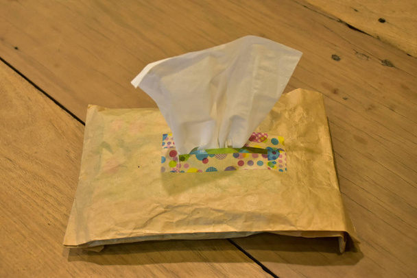 Enfoque en una caja de pañuelos hecha de cartón está en la mesa en la cafetería por la noche
 - Foto, Imagen