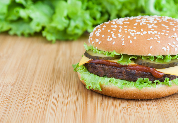 гамбургер з м'ясною котлетиною та кетчупом на дерев'яній тарілці
 - Фото, зображення