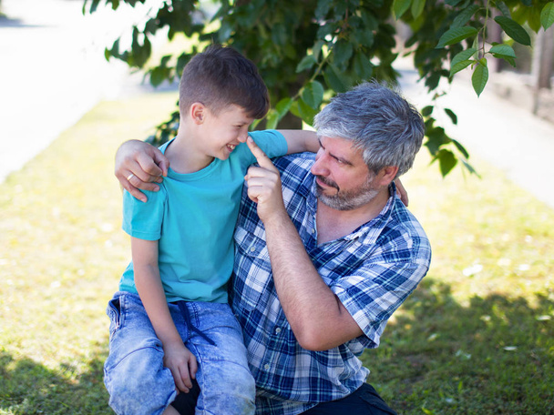 Father as lie detector, pushing sons nose, outdoors - Photo, Image