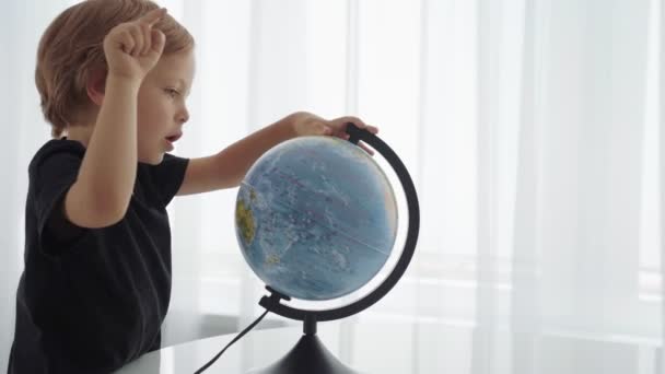 Cute caucasian boys spining a globe and dreaming about travel. - Materiał filmowy, wideo