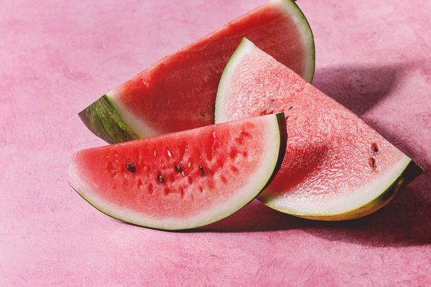 Ripe sliced watermelon over pink texture background. - Foto, afbeelding