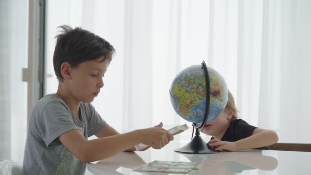 Two caucasian boys spin counting money for travel - Materiaali, video