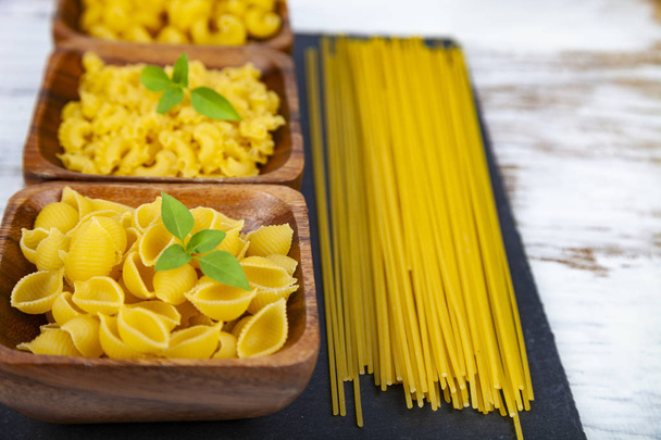 Various pasta in wooden bowls on a wooden background close-up. - Foto, afbeelding