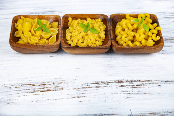Various pasta in wooden bowls on a wooden background close-up. - Photo, image