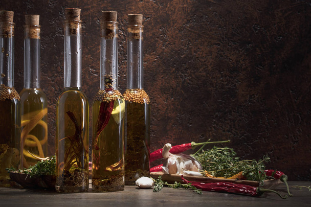 Butelki z oliwy z oliwek na starym drewnianym stole. Oliwa z oliwek z różnych przypraw i ziół. Miejsce. - Zdjęcie, obraz