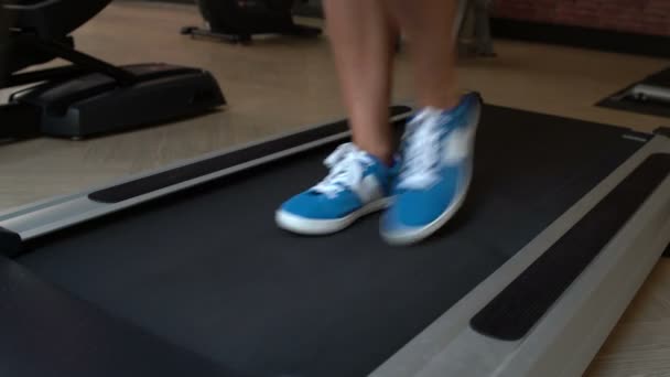 Womens feet are on the treadmill at the gym - Záběry, video