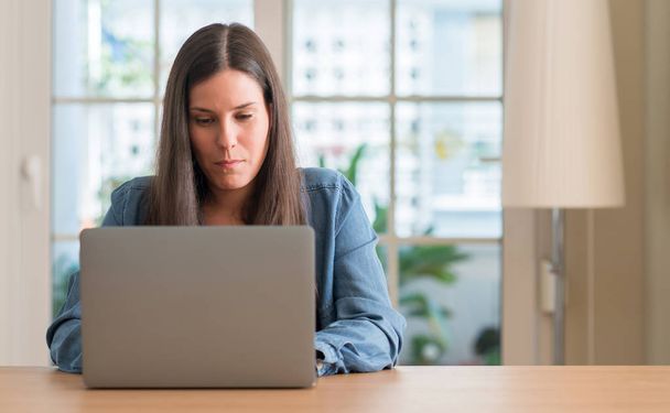 Fiatal nő használ a laptop otthon, a gondolkodás súlyos Szúró Szembenéz magabiztos kifejezés - Fotó, kép