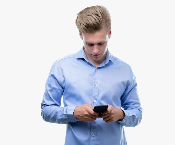 junger schöner blonder Mann mit Smartphone und selbstbewusstem Gesichtsausdruck, der ernsthaft denkt - Foto, Bild