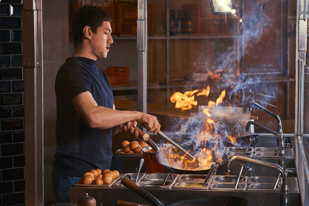 Cucini sono verdure di fritto con spezie e salsa in un wok su una fiamma. Processo di cottura in un ristorante asiatico
. - Foto, immagini
