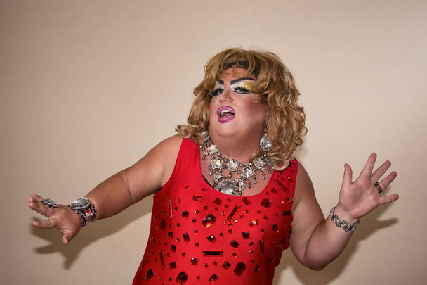 Funny travesty actor. Drag queen in red. Feelings and emotions. Fat man and make-up. Game - Фото, изображение