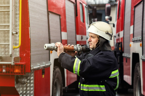 Pompier (pompier) en action debout près d'un camion de pompiers. Sécurité d'urgence. Protection, sauvetage du danger
. - Photo, image