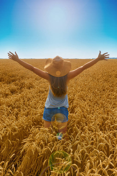 Jonge mooie blonde meisje gelukkig kijken naar de zon in het Zenit. Ze is het dragen van een hoed. Transmissie veld. Achteraanzicht. - Foto, afbeelding