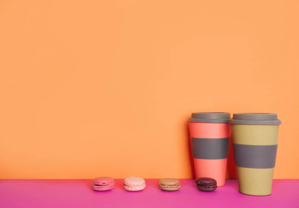 Cup of coffee to go with macaron on yellow and pink background with place for your text. - Foto, immagini