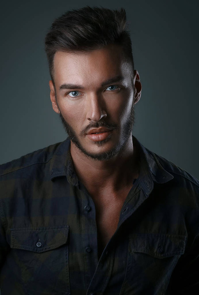 Close up portrait of a handsome young man with brave manly face on dark background. Caucasian man staring serious, male beauty, cosmetics. - Foto, imagen