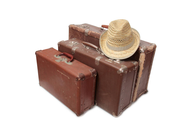 Old suitcase and a straw hat on a white background - Foto, afbeelding