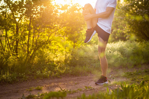 athletischer junger Mann, der bei Sonnenuntergang im Park läuft und Musik hört. Gesunder Lebensstil - Foto, Bild