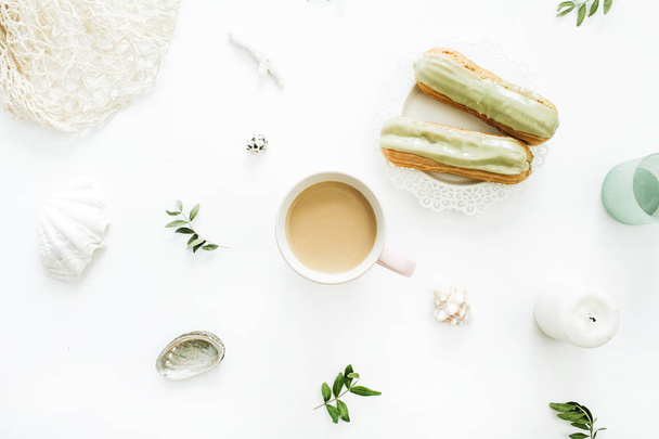 Πρωινό έννοια με κούπα καφέ, φιστίκι κέικ, φύλλα και κοχύλια σε άσπρο φόντο. Επίπεδη lay, κορυφαία θέα στυλ σύνθεσης των τροφίμων. - Φωτογραφία, εικόνα
