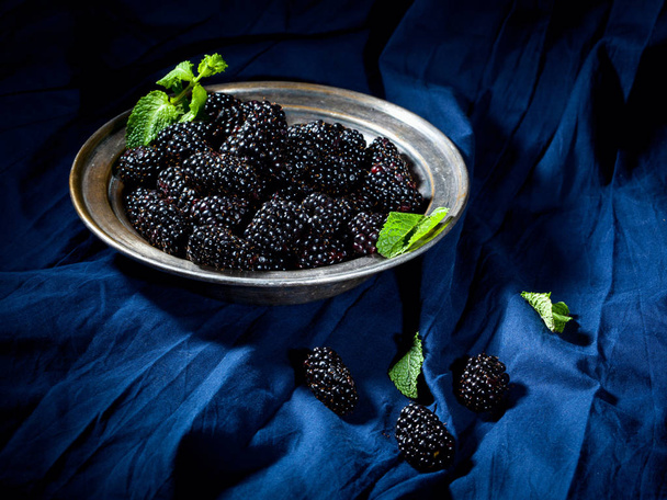 Vintage plate with blackberries and mint leaves on dark blue fabric - Φωτογραφία, εικόνα