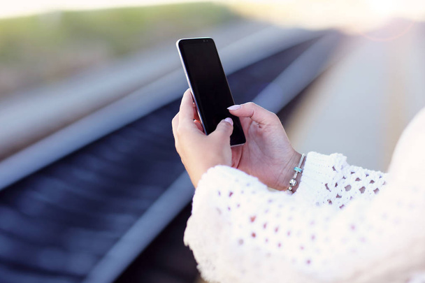 Ręczne trzymanie smartfona z tłem dworca kolejowego - Zdjęcie, obraz