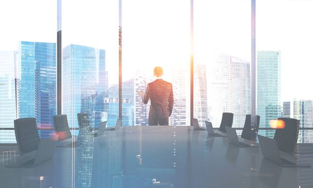 Businessman standing in an office meeting room with black chairs and table. Panoramic windows. 3d rendering mock up toned image double exposure - Photo, Image
