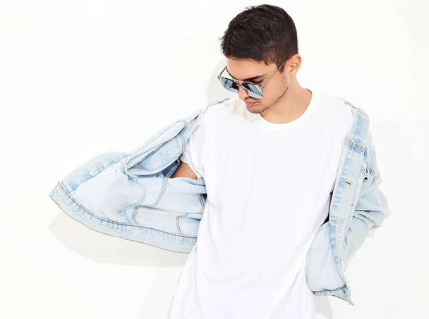 Portrait of handsome young model man dressed in jeans clothes in sunglasses posing on white background. Isolated - Foto, immagini