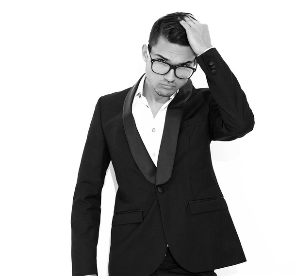 portrait of handsome fashion stylish hipster lumbersexual businessman model dressed in elegant black classic suit posing near white wall in studio. Metrosexual - Φωτογραφία, εικόνα