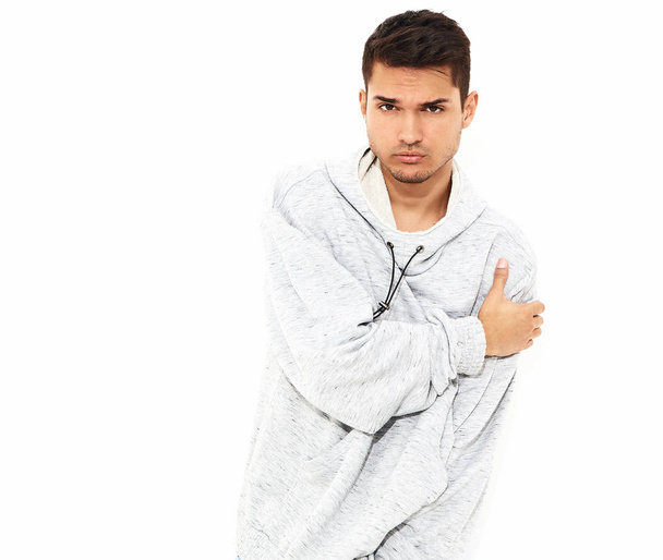 Portrait of young handsome model man dressed in gray casual hoodie clothes posing on white background. Isolated - Zdjęcie, obraz