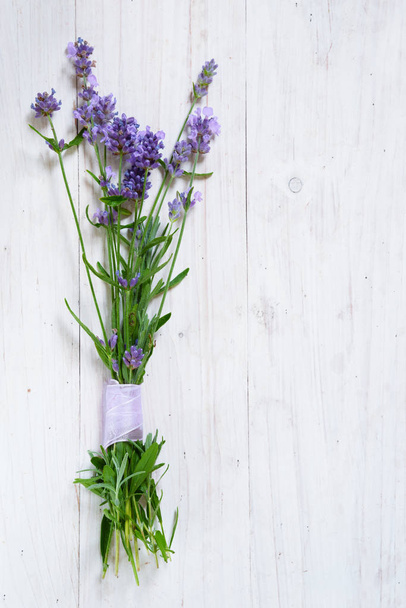 Bündel blühender Lavendelzweige auf weiß lackiertem Holzgrund mit Kopierraum, vertikal - Foto, Bild