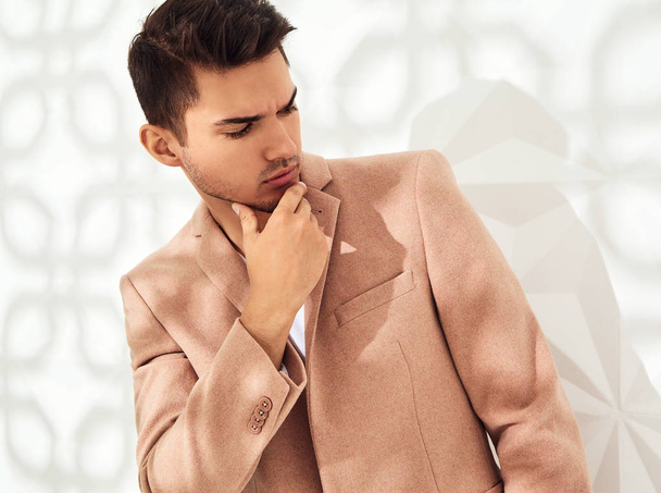 Модна стильна модель, одягнена в елегантний світло-рожевий костюм, позує біля білої стіни в студії. Метросексуальний
 - Фото, зображення