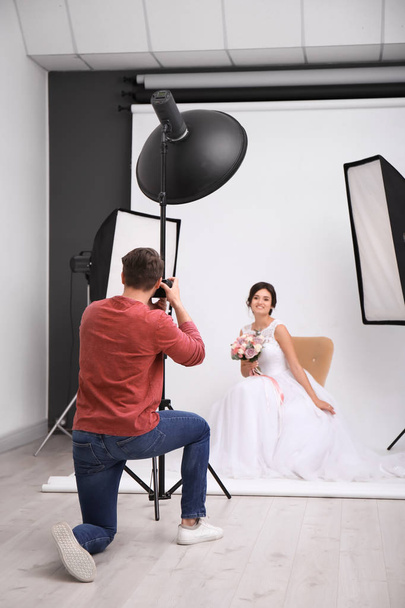Professional photographer taking photo of beautiful bride in studio - Zdjęcie, obraz