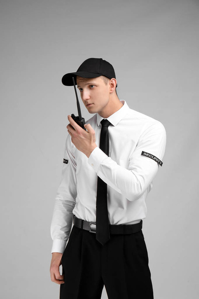 Male security guard using portable radio transmitter on color background - Foto, Bild